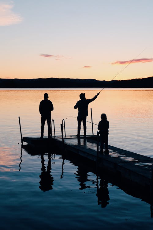 三人在一个木制的渔船码头 · 免费素材图片