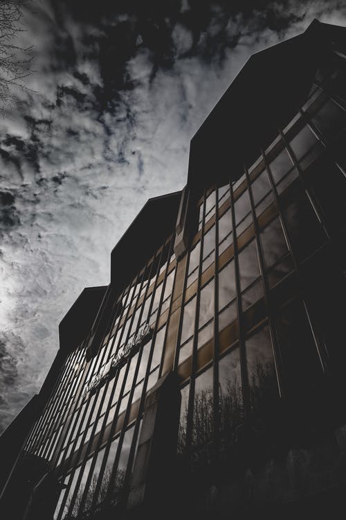 棕色混凝土建筑与玻璃窗在灰色的天空下 · 免费素材图片