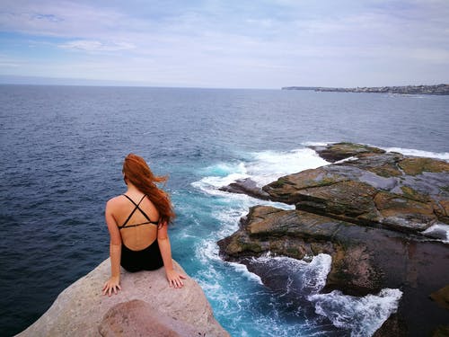 女人在水面附近的岩石夹上穿monokini · 免费素材图片
