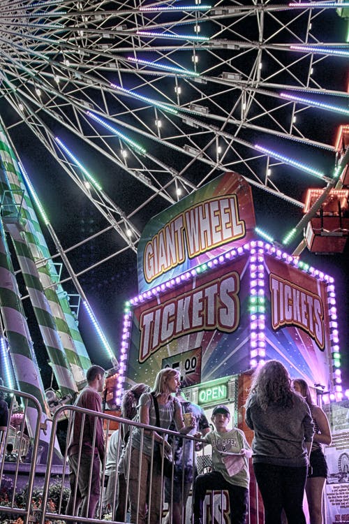 女人站在金属栅栏附近戴着黑帽子的男孩 · 免费素材图片