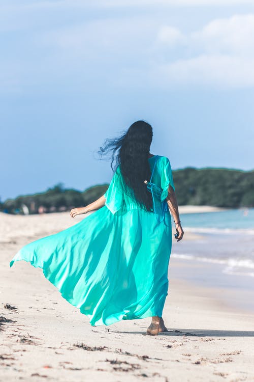 女人走近水体时穿蓝绿色的衣服 · 免费素材图片