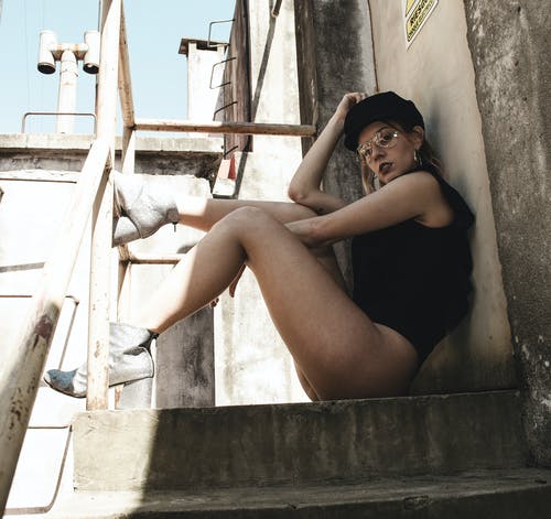 女人穿着黑色无袖上衣，坐在楼梯上 · 免费素材图片