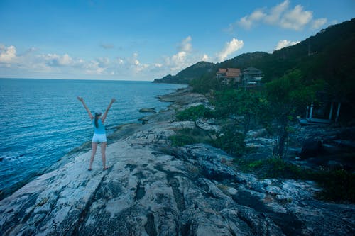 女人穿着蓝色背心站在水的旁边 · 免费素材图片