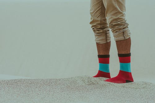 穿着红色的袜子，站在沙滩上的人 · 免费素材图片
