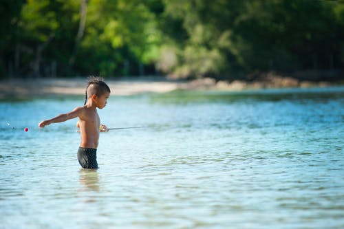裸露的男孩穿着黑色短裤站在水域 · 免费素材图片