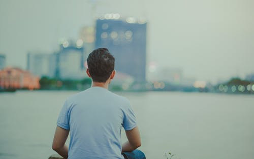 穿蓝色衬衫的男人坐在高层建筑上看的照片 · 免费素材图片