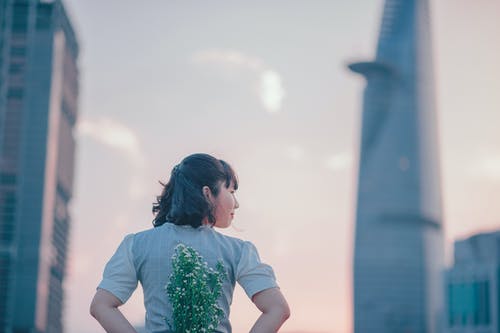 在她的背上捧着鲜花的灰色上衣的女人的照片 · 免费素材图片