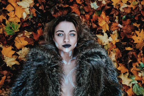 黑色皮大衣躺在棕色枫叶上的女人 · 免费素材图片