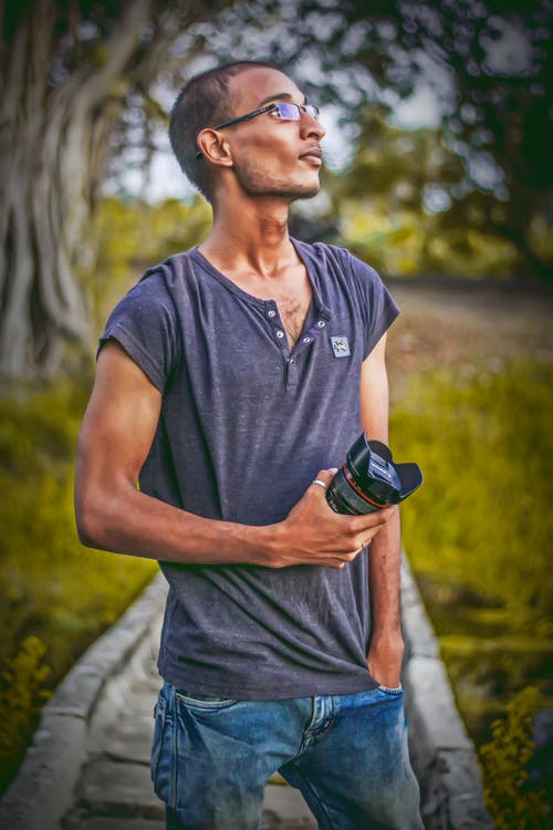 浅色摄影的男子穿着灰色t恤拿着单反相机镜头 · 免费素材图片
