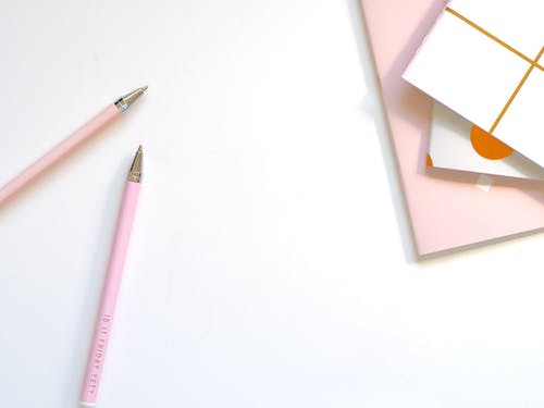 桌上的两个粉红色圆珠笔 · 免费素材图片