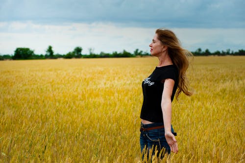 女人穿着黑衬衫包围草 · 免费素材图片