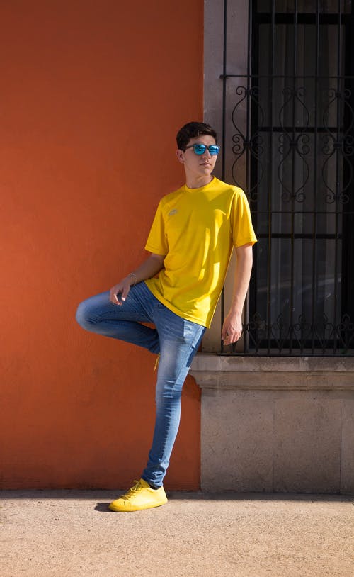 男人穿着黄色圆领t恤和蓝色牛仔牛仔裤 · 免费素材图片