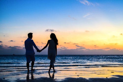 男人和女人牵手走在海边日出 · 免费素材图片