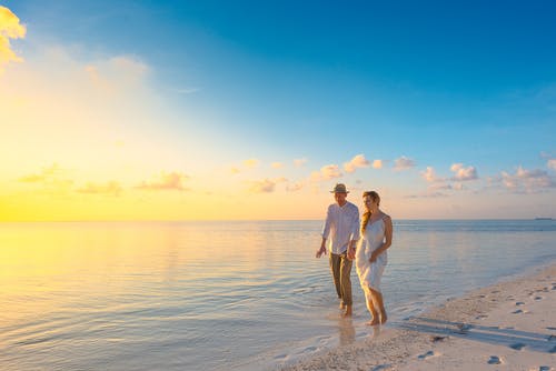 夫妻在日落期间在海边穿白色上衣上行走 · 免费素材图片