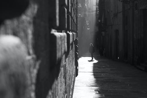 在灰度摄影中巷子里走的人 · 免费素材图片