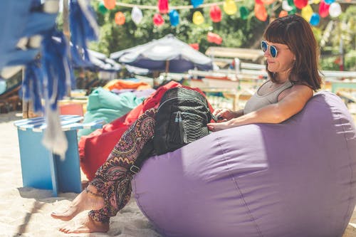 女人穿着灰色背心坐在紫色豆袋 · 免费素材图片