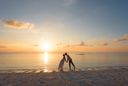 男人和女人站在岸边接吻 · 免费素材图片