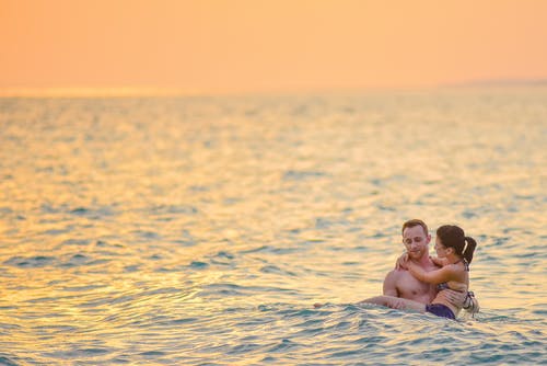男人和女人在海滩游泳 · 免费素材图片