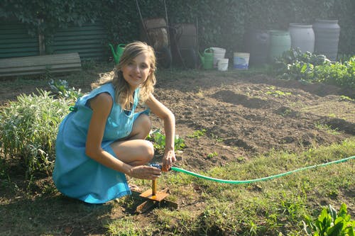照片女人拿着绿色的花园软管 · 免费素材图片