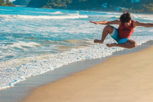 一名男子在沙滩上跳跃的摄影 · 免费素材图片