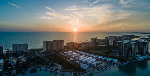 夕阳下海洋附近的摩天大楼 · 免费素材图片