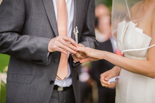 新郎在他的新娘上戴上结婚戒指的照片 · 免费素材图片