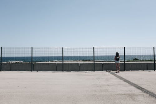 站在栅栏和水体附近的女人 · 免费素材图片