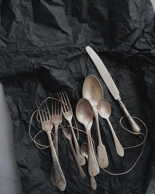 黑色布上的不锈钢餐具的照片 · 免费素材图片