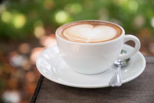 拿铁咖啡在白色陶瓷杯碟与微距摄影 · 免费素材图片