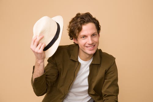 男人穿着棕色礼服衬衫拿着白色的软呢帽 · 免费素材图片