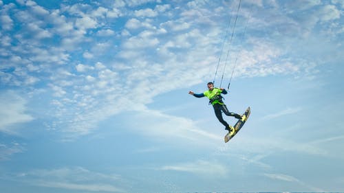 男人穿着绿色和黑色的潜水衣骑滑水 · 免费素材图片