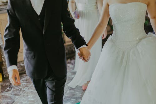 女人穿着白色的婚纱，与男人牵手散步时 · 免费素材图片