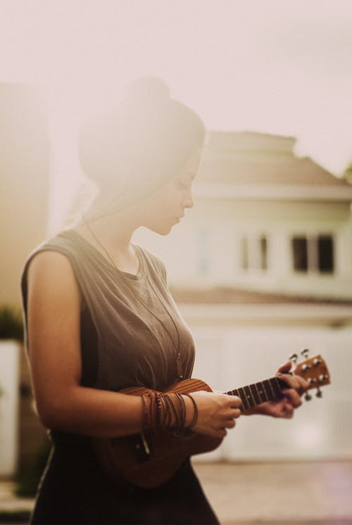 玩夏威夷四弦琴时穿棕色无袖连衣裙的女人 · 免费素材图片