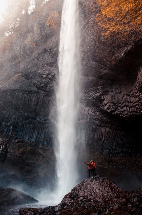 白天在瀑布旁边的两个人 · 免费素材图片
