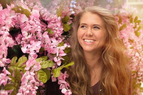 站在粉红色的花朵旁边的女人的照片 · 免费素材图片