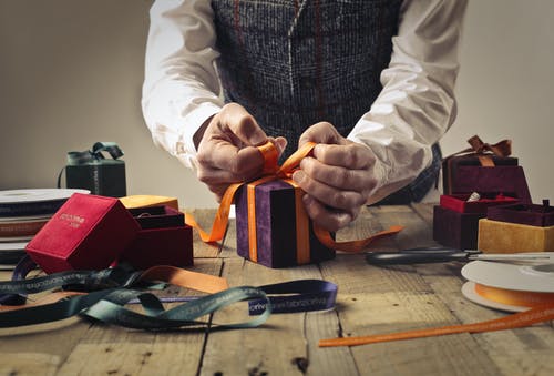 人在紫色礼品盒上绑丝带 · 免费素材图片