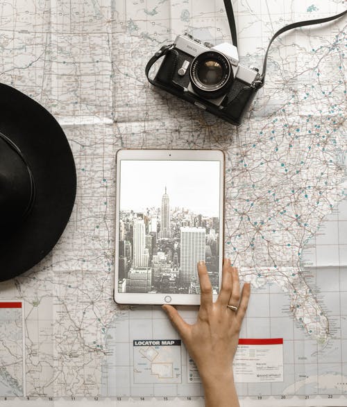 在黑帽旁边的世界地图上人触摸银ipad的平躺摄影 · 免费素材图片