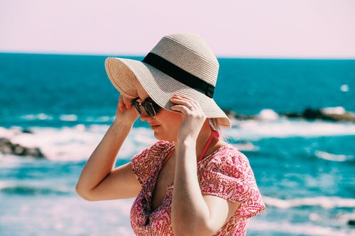 女人的选择性焦点照片白天在水体后面戴米色遮阳帽 · 免费素材图片