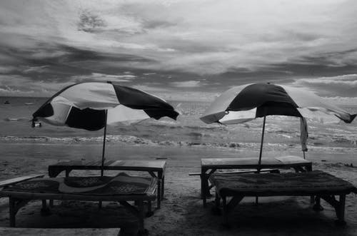 海边的两个野餐桌的灰度摄影 · 免费素材图片