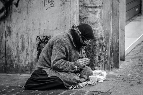 人在人行道上祈祷与食物在前面的灰度摄影 · 免费素材图片