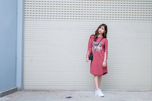 站在卷顶门旁边穿红色连衣裙的常设女人 · 免费素材图片