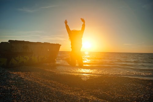 黄金时段在海边跳的人 · 免费素材图片