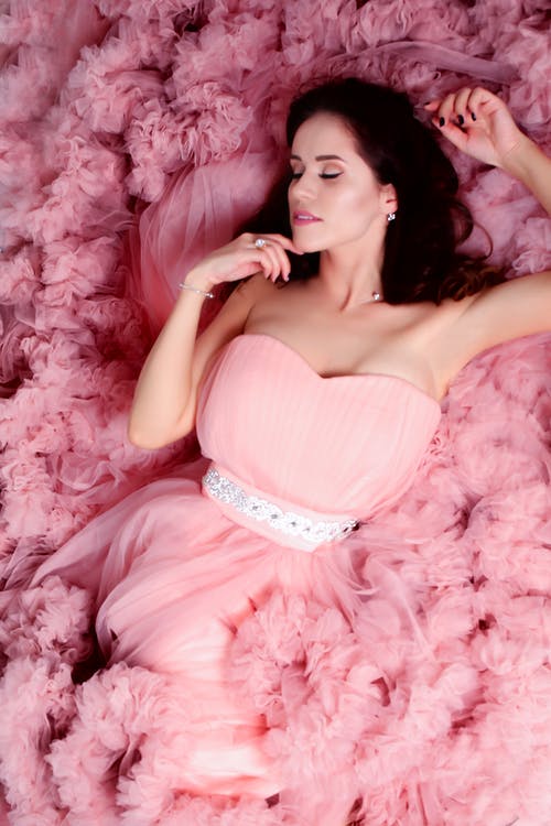 说谎的女人穿着粉红色的甜心领口连衣裙 · 免费素材图片