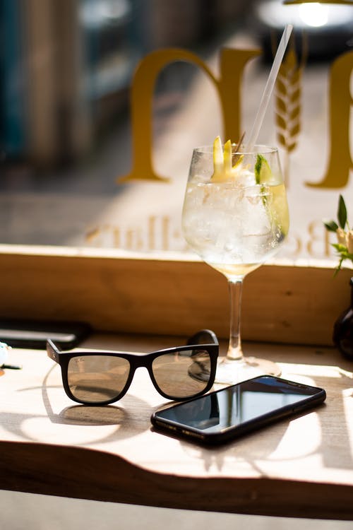 Android智能手机和太阳镜旁边的酒杯 · 免费素材图片