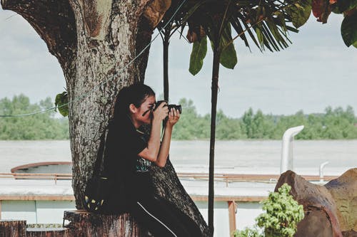 女人拍照到树附近 · 免费素材图片