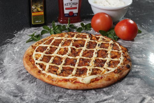 两个红番茄旁边的烤的比萨 · 免费素材图片