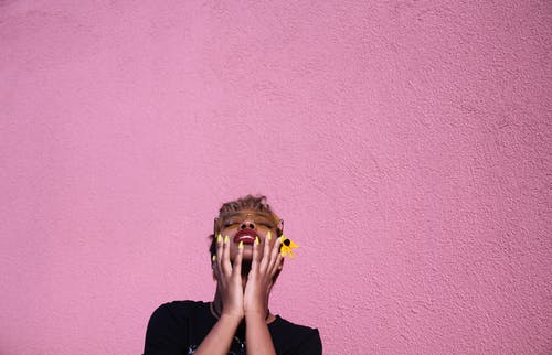 时髦的年轻黑人妇女感人的脸，而回头扔在粉红色的背景上 · 免费素材图片