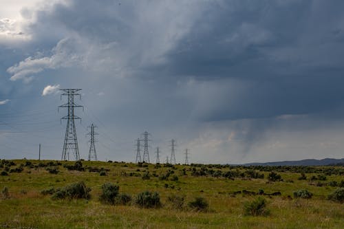在白云和蓝天下的绿色田野上的灰色电岗 · 免费素材图片