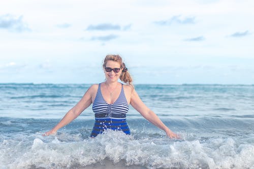 在海洋上穿蓝色和灰色泳装的女人 · 免费素材图片