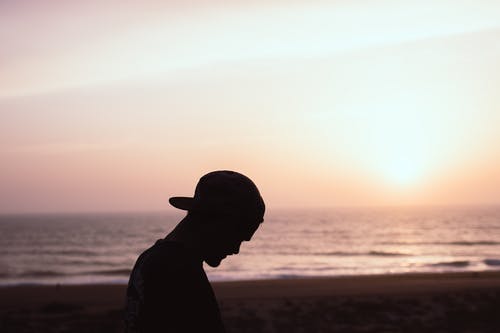 男子戴着帽子在海滩上的剪影 · 免费素材图片